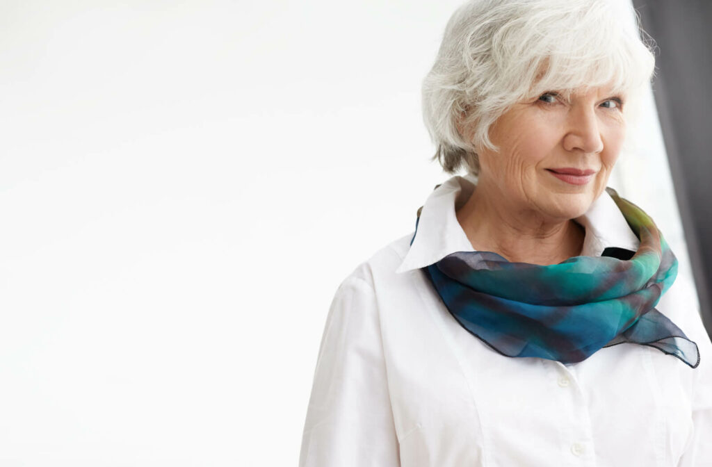 "A fashionable senior woman with a confident look wearing a stylish, colourful scarf and a vintage white blouse."