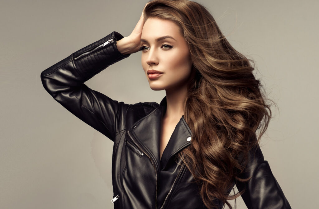 A woman with long wavy hair wearing a black leather jacket.