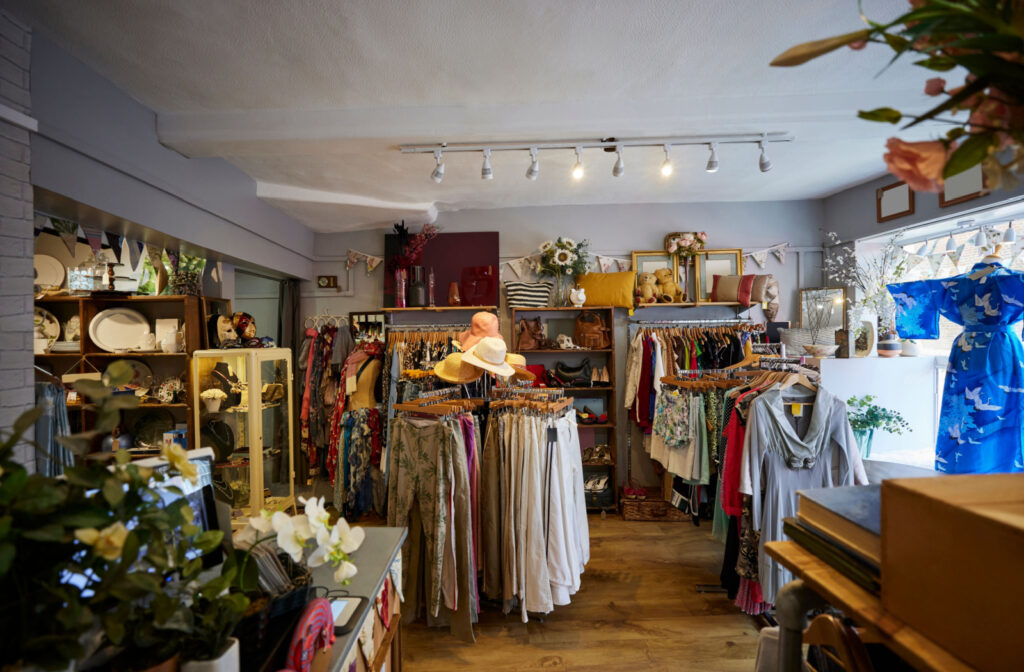 The interior of a consignment shop with plenty of colourful clothes, homewares, and accessories on display.