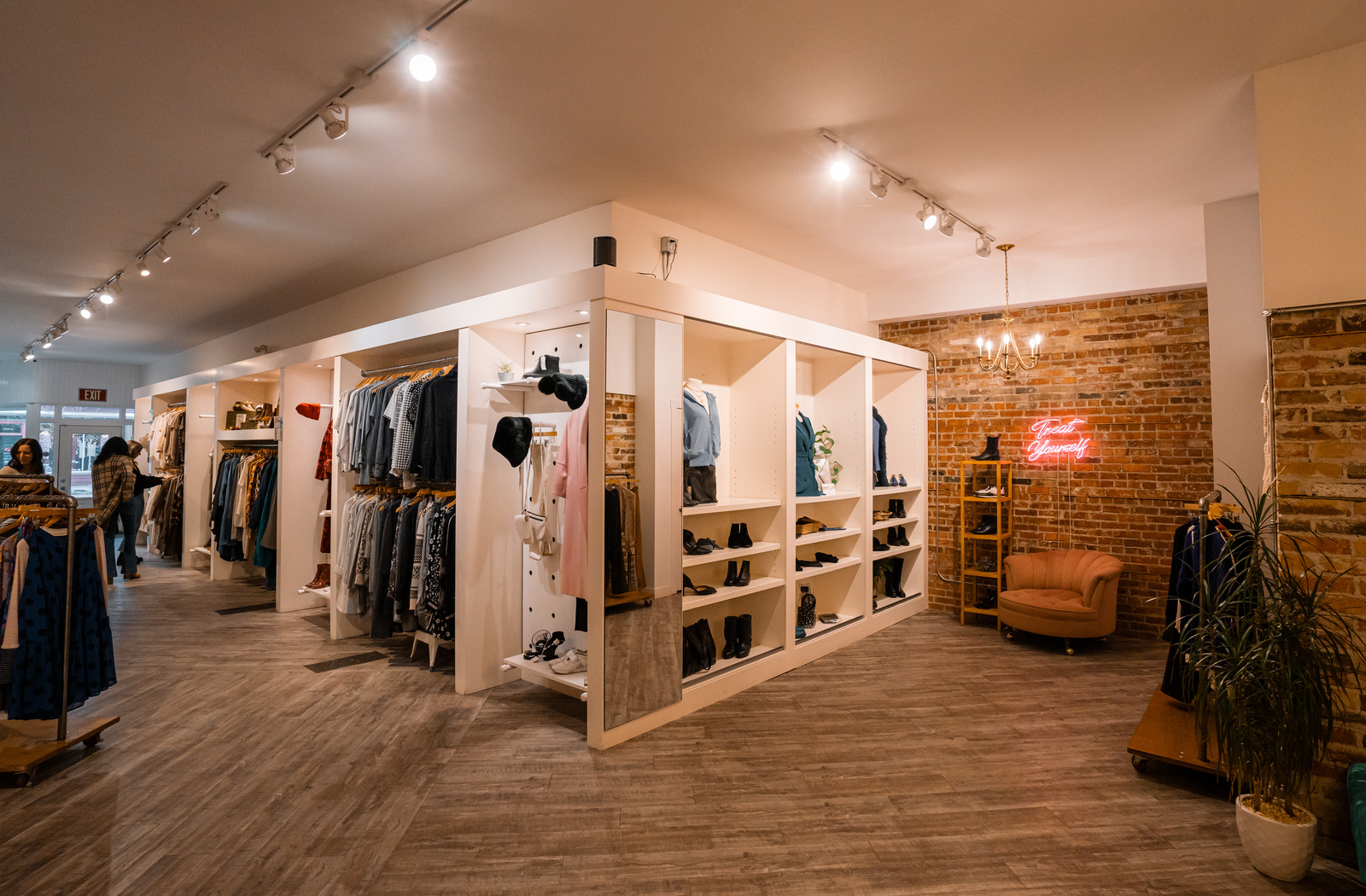 An interior view of The Peacock Boutique Consignment, with an assortment of shoes, accessories, blouses, shirts, and other clothing displayed on shelves and hangers.