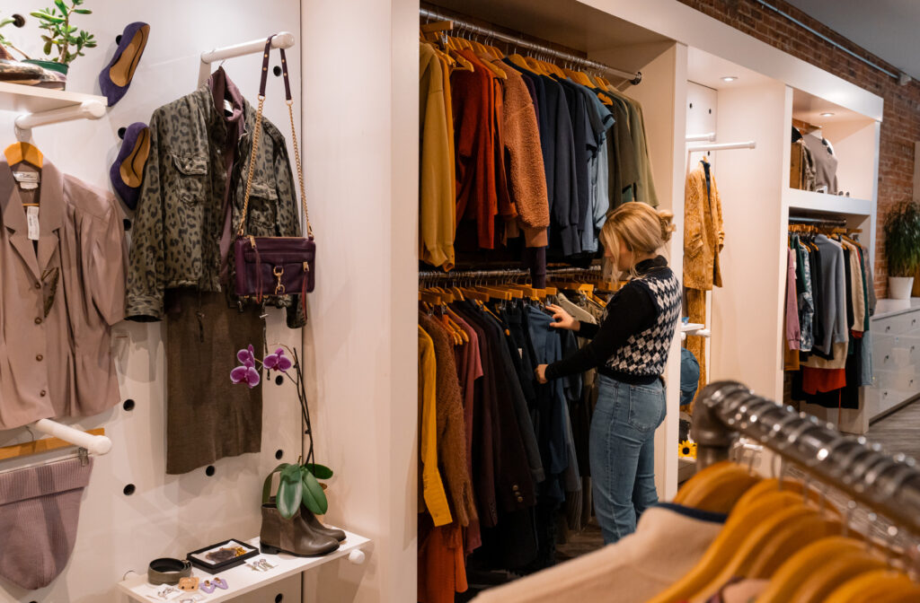 A Peacock Boutique shopper browses a hanging row of consigned outerwear.
