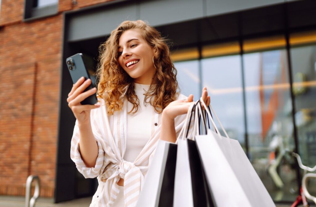 A young woman checks the status of her online order on her phone after picking up her order form a local boutique.