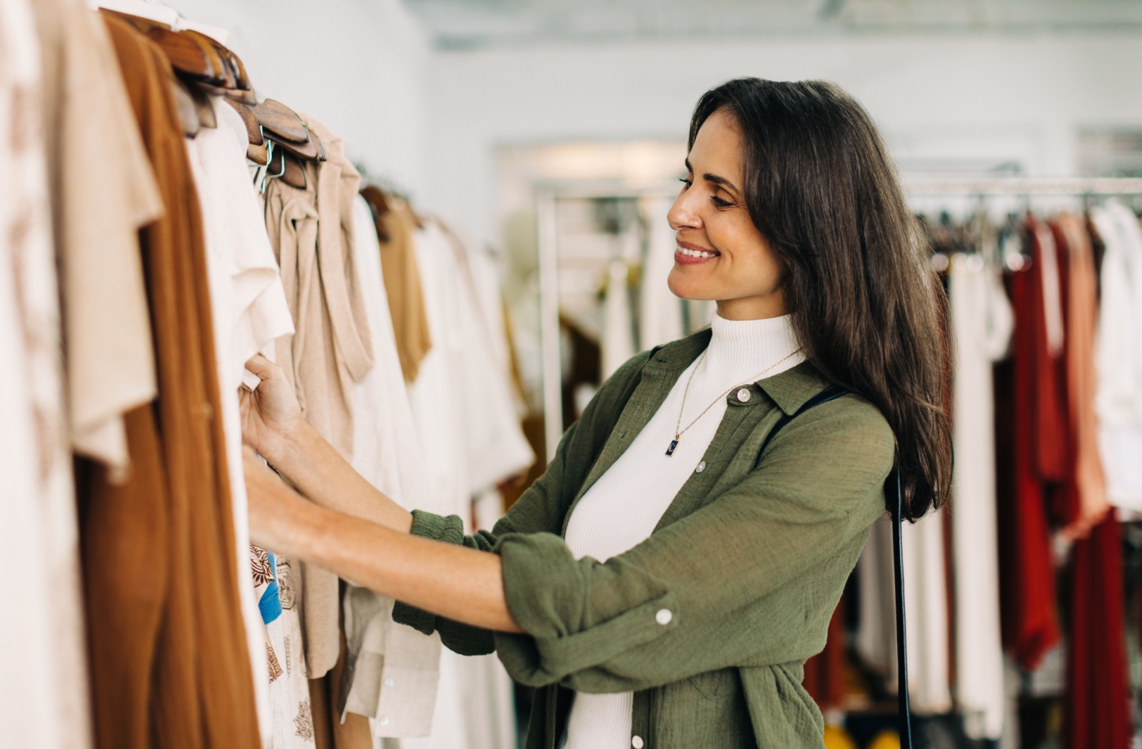 A woman browses hand-selected clothing while consignment shopping.