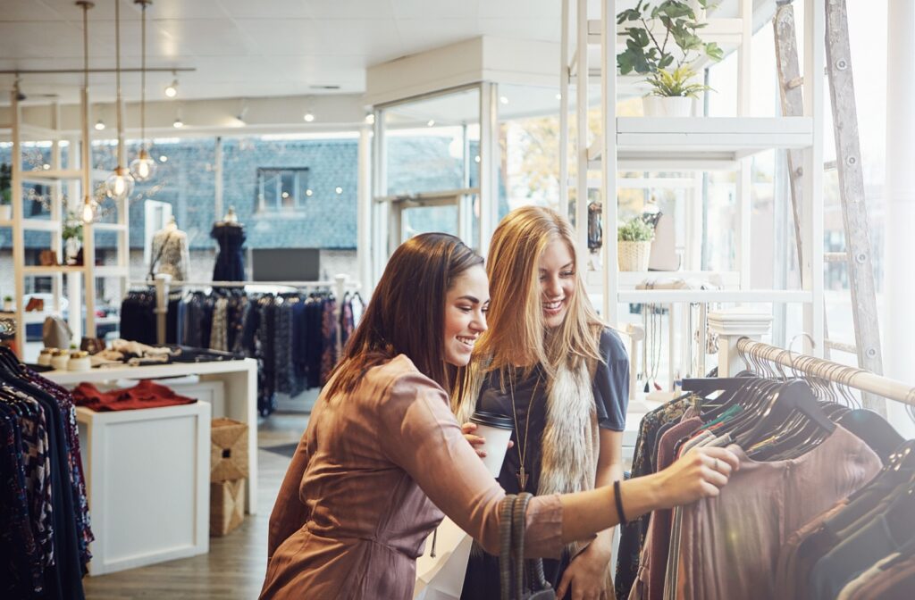 Two people are looking through some unique pieces on a clothing rack at a consignment boutique.