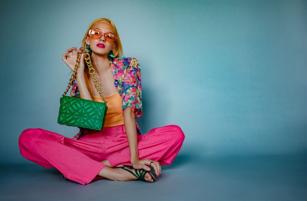 A person poses with a variety of bold, colourful accessories.