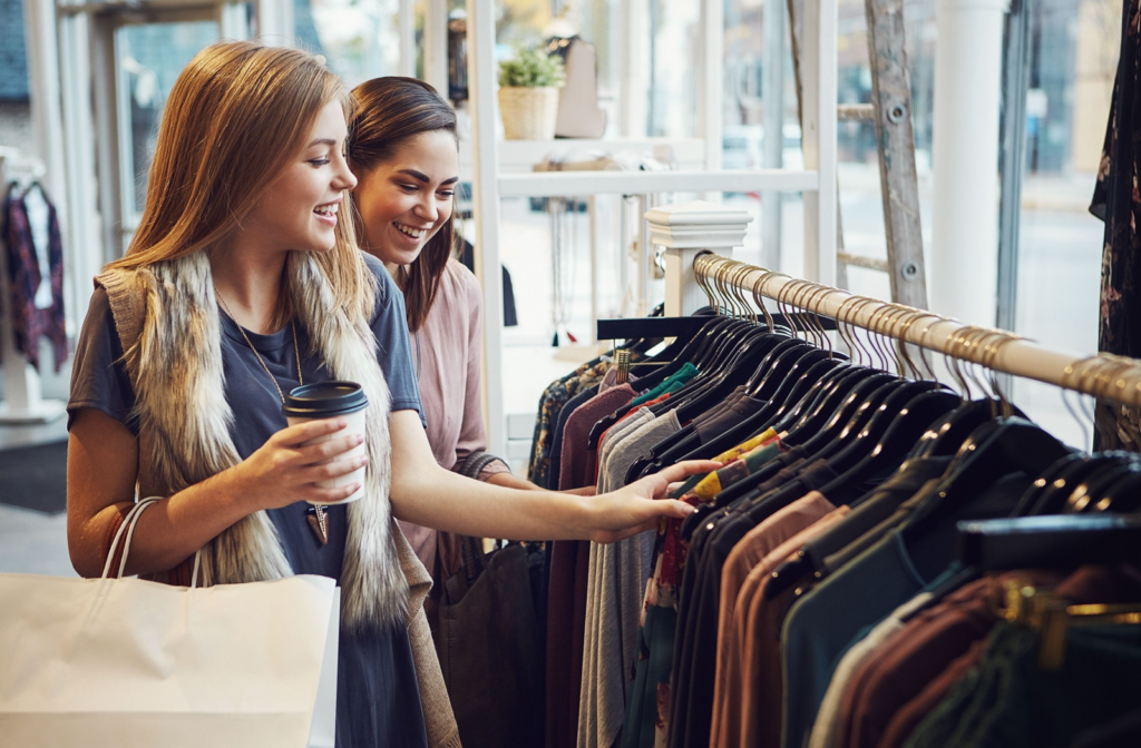 Two people shopping in a store, browsing through a clothing rack.